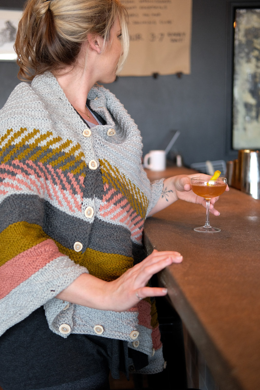 Kelly sitting at a bar in her Om shawl