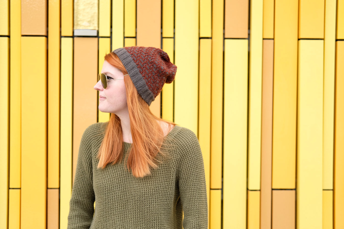 Lauren in sunglasses and her Tincture hat in front of bright yellow wall