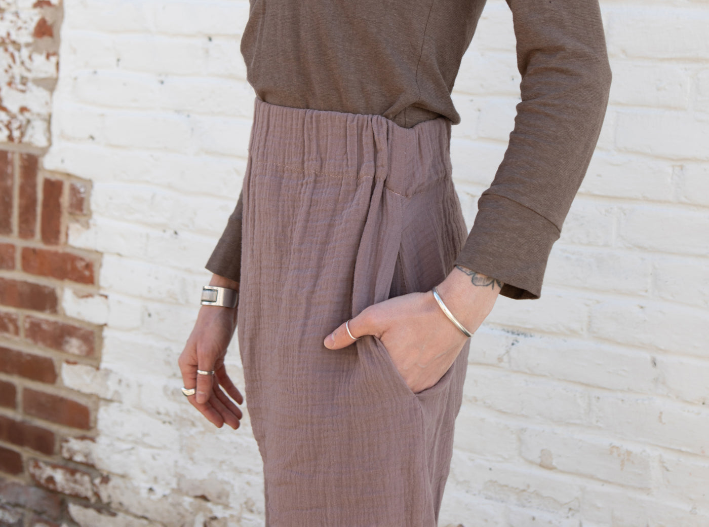 This is an image of a close up of Leaf's Zola Double Gauze in Taupe Free Range Slacks, with their hand placed in one of the side pockets. 