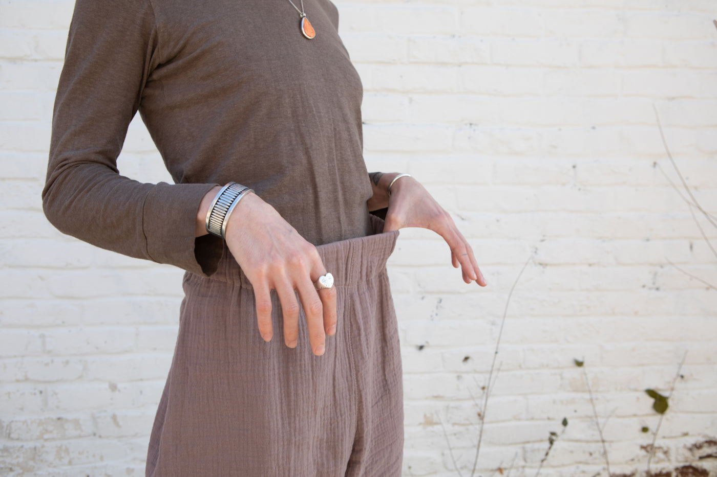 This is an image of Leaf's Zola Double Gauze in Taupe Free Range Slacks, with a close up of their hands on the waist band. 