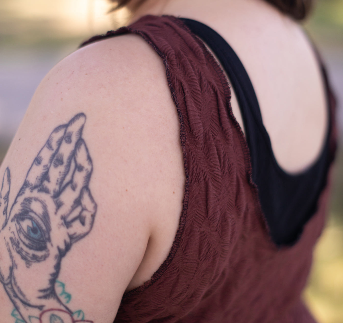 This is an upclose photo of the shoulder and back details of a mauve sleeveless jumpsuit. 