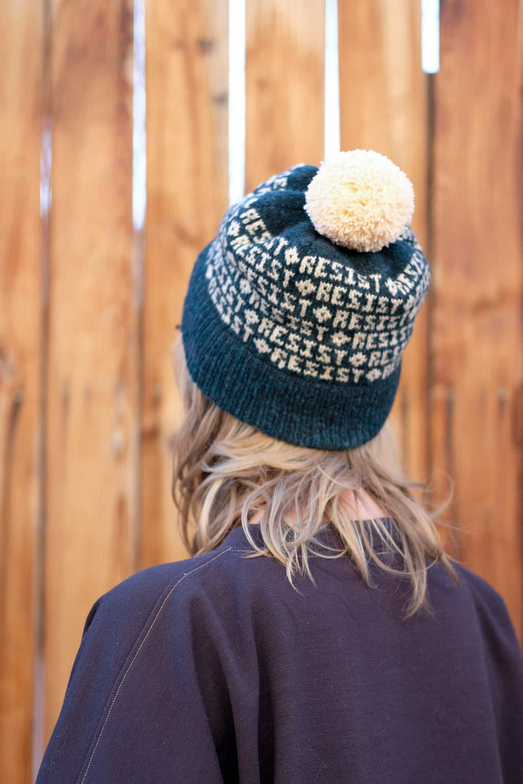 Amber in her Resist Hat from the back with a large peach pompom