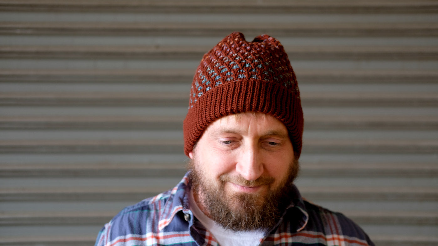 Scott in his rusty Honey Drudger hat in front of a metal wall