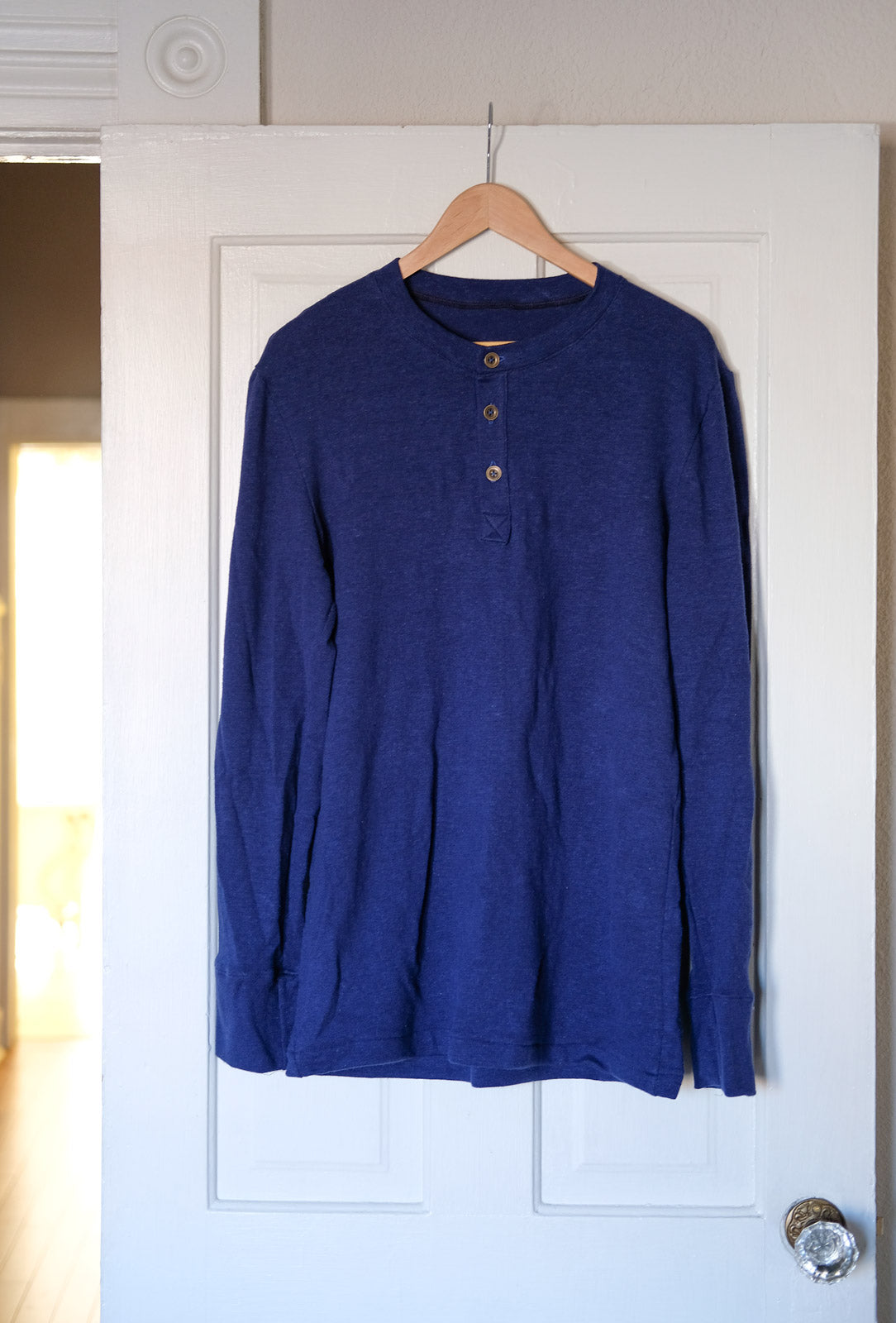 Royal Blue Thread Theory Henley hanging on a door