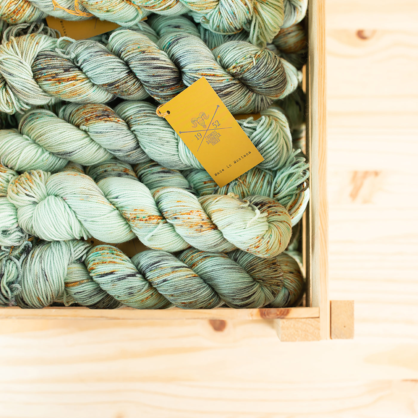 This is an image of a wooden box full of mint colored yarn. 