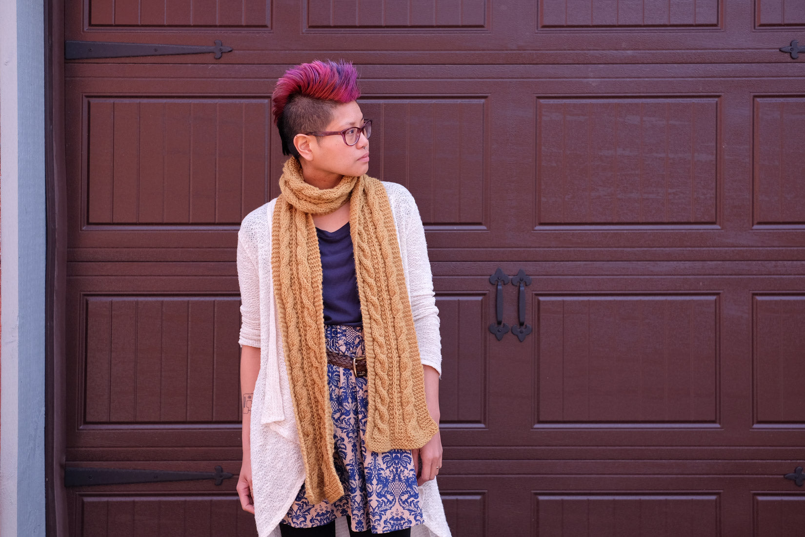 Woman with pink mohawk wearing mustard-yellow cabled scarf.