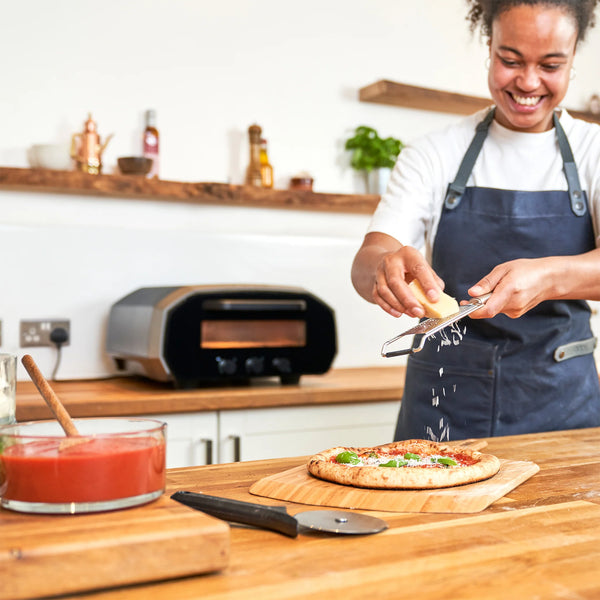 ooni volt 12 electric pizza oven with person making a pizza 