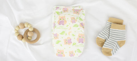 Newborn Happy Little Camper diaper next to socks and teething ring