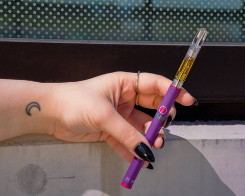 A white girl's hand with pointy black nails is holding an ultra purple Ooze Twist Slim Pen 2.0 to show the flex temp dial.