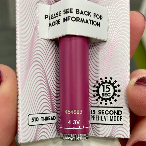 A close-up shot of a pink Ooze Slim Twist Vape Battery, in the original inner packaging. It is showing the warranty number on the bottom of the battery.