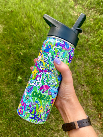 A girl holds the Ooze Chroma 18oz water bottle outside in the lawn