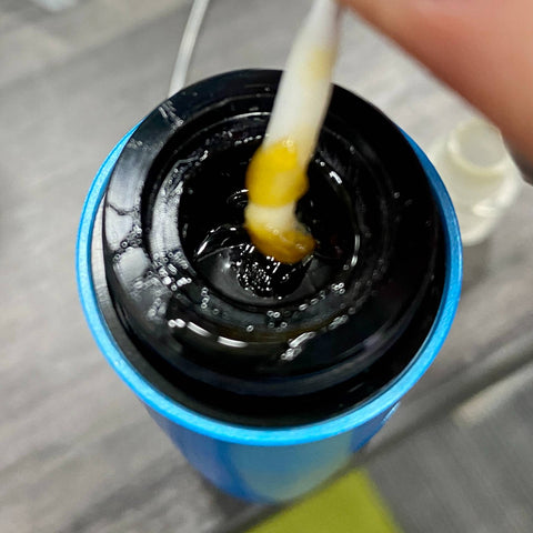Using a micro swab to clean the dirty base of an Ooze Booster. There is a lot of sticky concentrate residue.
