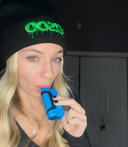 Blonde influencer @gethighwithkathy wears her Ooze beanie while hitting her blue Ooze Duplex 2