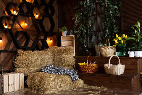 A cozy, fall-themed photo backdrop with hay bales, candles on the wall, and baskets.