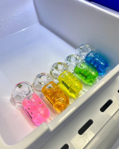 The 5 colors of the Ooze Cryo Bowl are lined up in a freezer drawer. From left to right they are pink, orange, yellow, green, and blue.