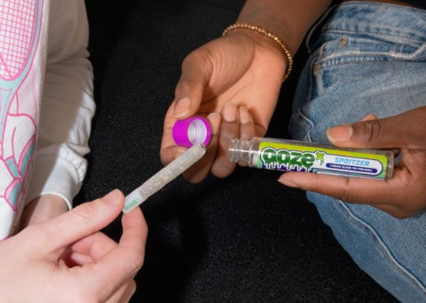 Two people taking an OozeX pre-roll out of the tube