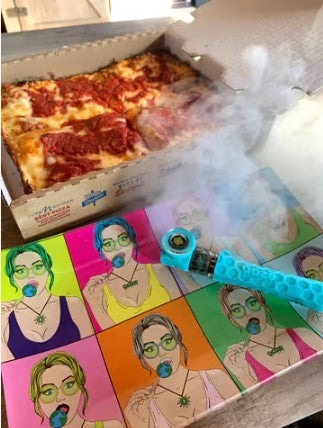 An Ooze Piper is packed on a rolling tray in front of a box of Detroit style deep dish pizza