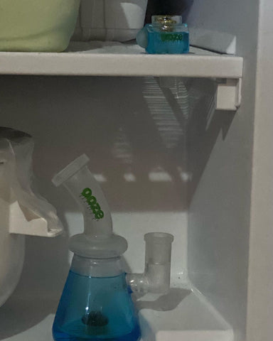 The Aqua Teal Ooze Glyco Glycerin Bong is chilling in a freezer. The bong is on a lower shelf, and the matching Glyco bowl is on the upper shelf.