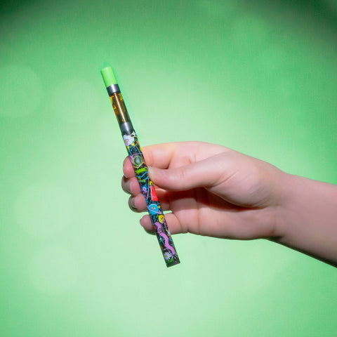 Holding up a Time Warp Ooze Twist Slim Pen 2.0 in front of a green background