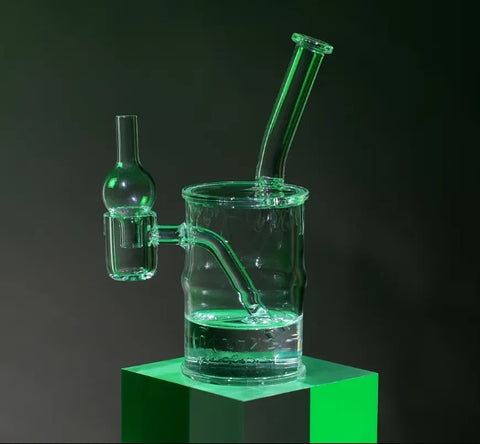 The Ooze Toxic Barrel quartz mini rig is filled with water and backlit with a green light to look like its glowing