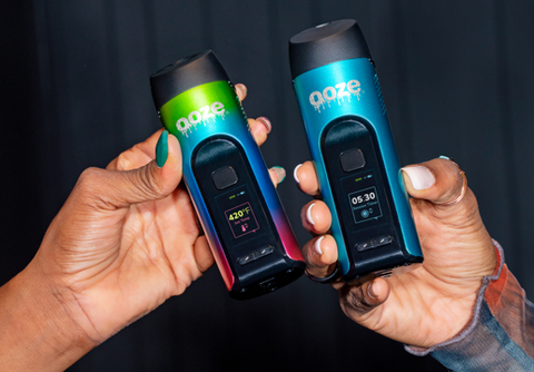 Two Ooze Verge dry herb vapes are held next to each other, both turned on