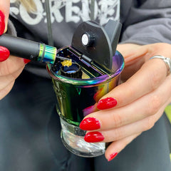 A girl is hold in rainbow Ooze Electro Barrel with the lid open while she loads a dab into the Onyx Atomizer
