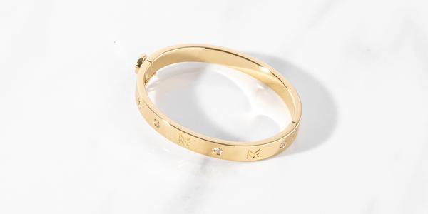Gold Miranda Frye Jewelry MF Cuff bracelet in a flat lay image.