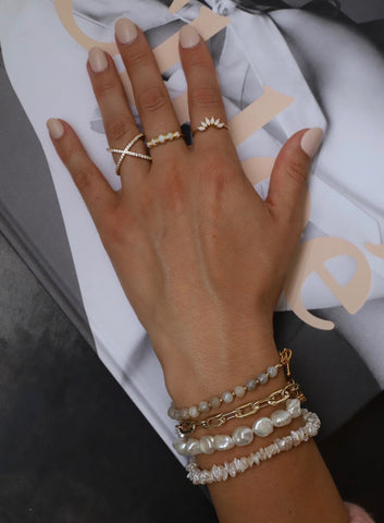 Woman's hand with stacked pearl and chain bracelets