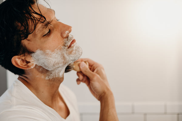 Image of a model applying shave cream on his face with a shave brush