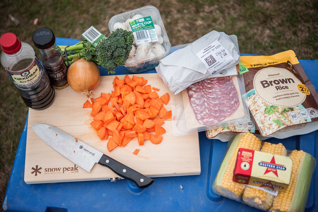 A snow peak chopping board and knife surrounded a selection of ingredients for cooking fried rice