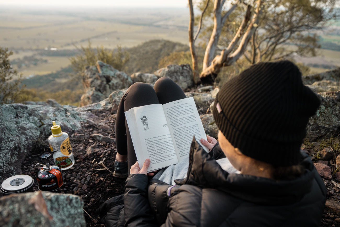 Chloe reading a book and drinking a cup of tea on top of The Rock near Wagga Wagga