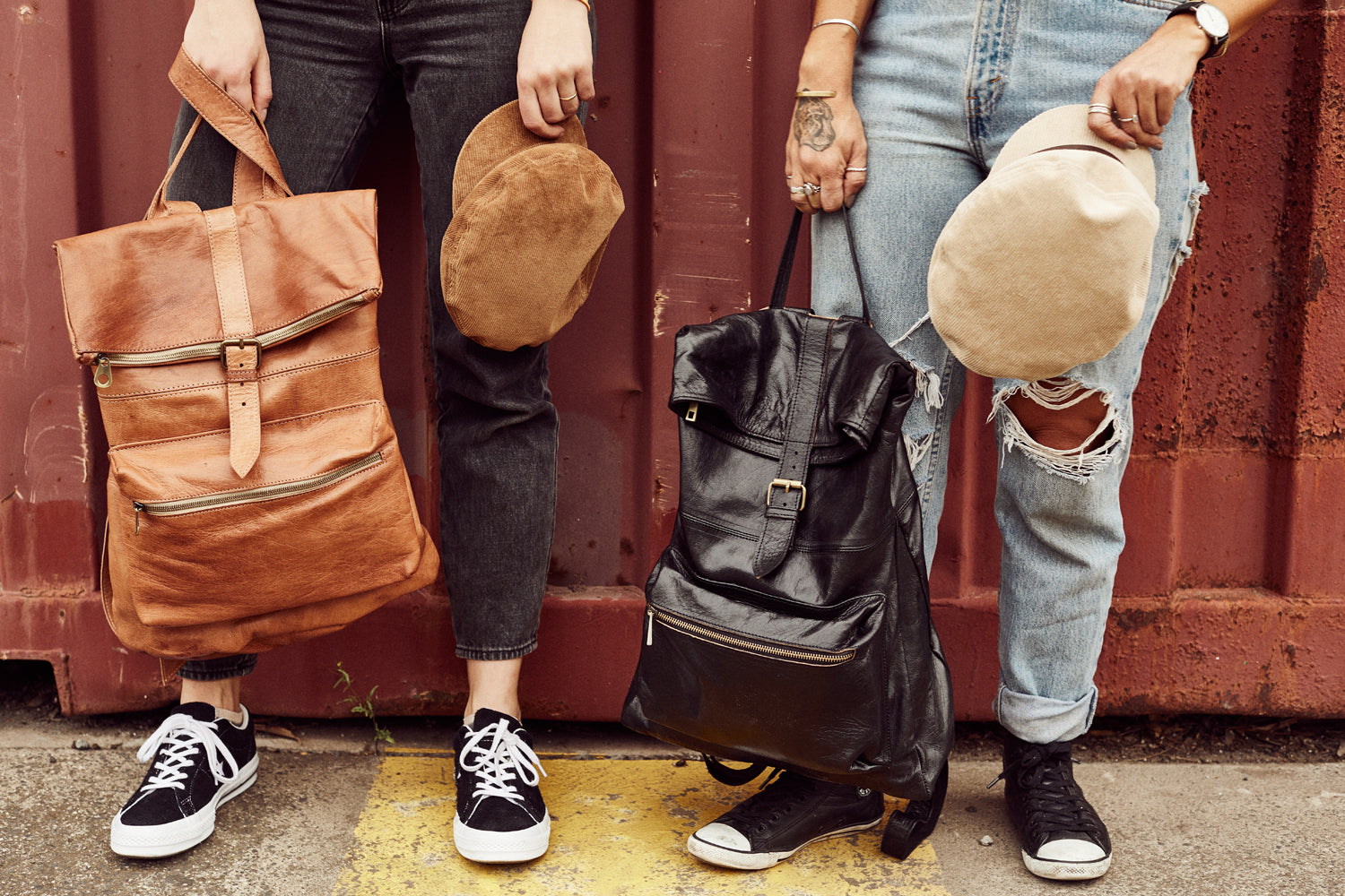 Rivers backpack held by two girls, they're wearing denim and converse sneakers 