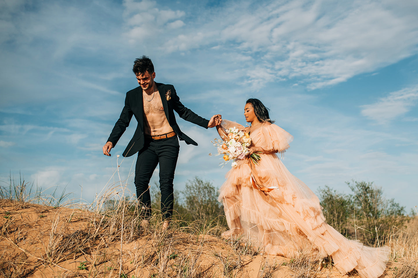 Couple climbing desert dunes joshua tree wedding