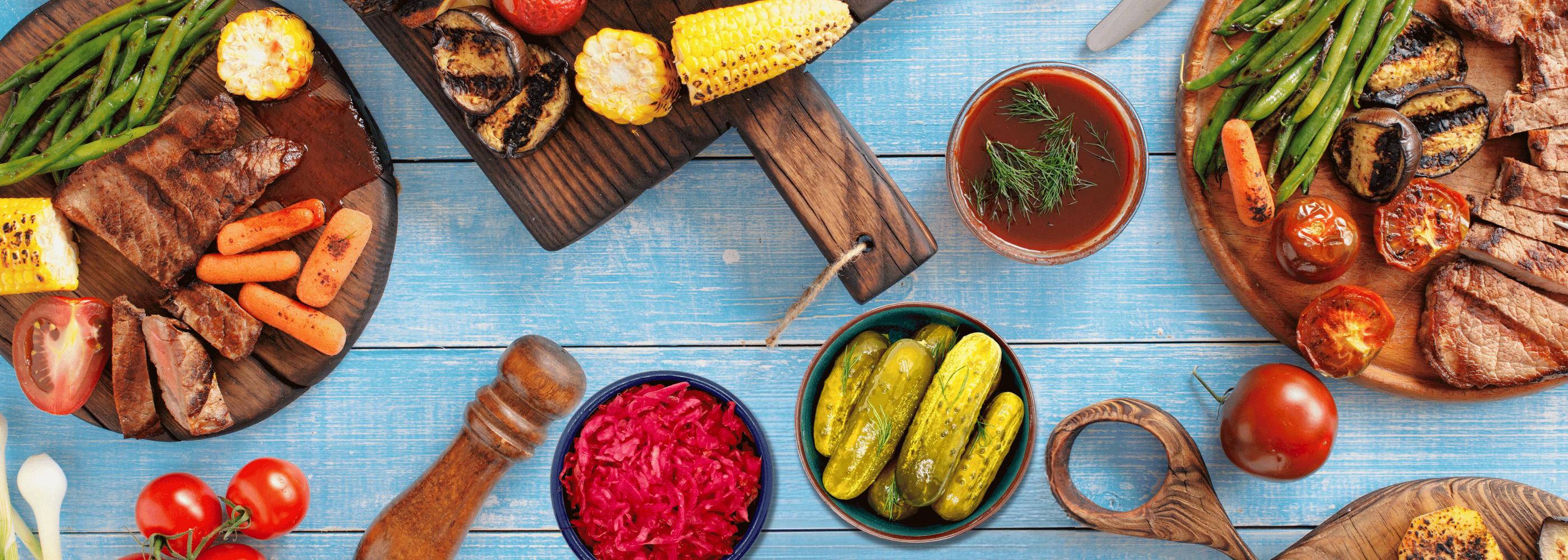 grilled foods with bowls of fermented sauerkraut and pickles on picnic table