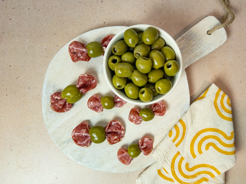 Bowtie salami appetizer with bowl of Olive My Pickle Pitted Butter Olives
