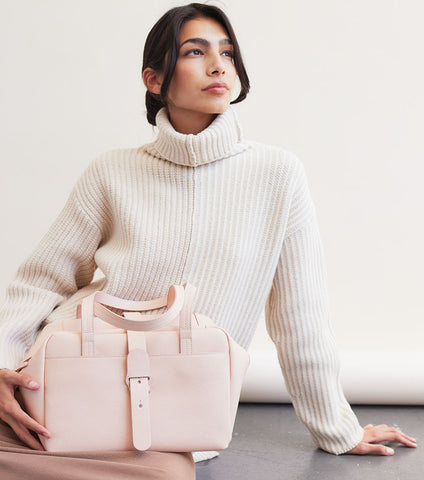 white turtleneck and soft pink handbag