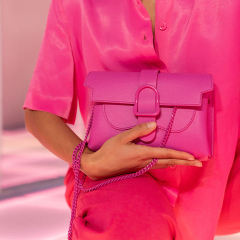 Woman holding pink handbag with matching pink chain