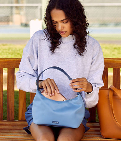 Model in baggy sweatshirt and a sporty purse