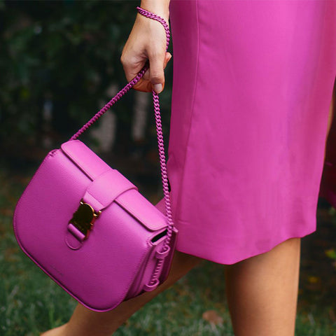 Woman wearing hot pink dress holding a pink bag by a matching chain