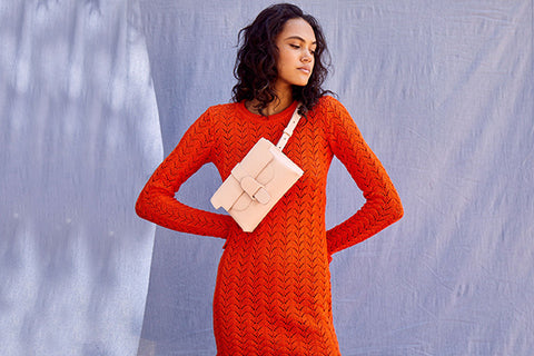 Woman in red dress with light pink belt bag across chest