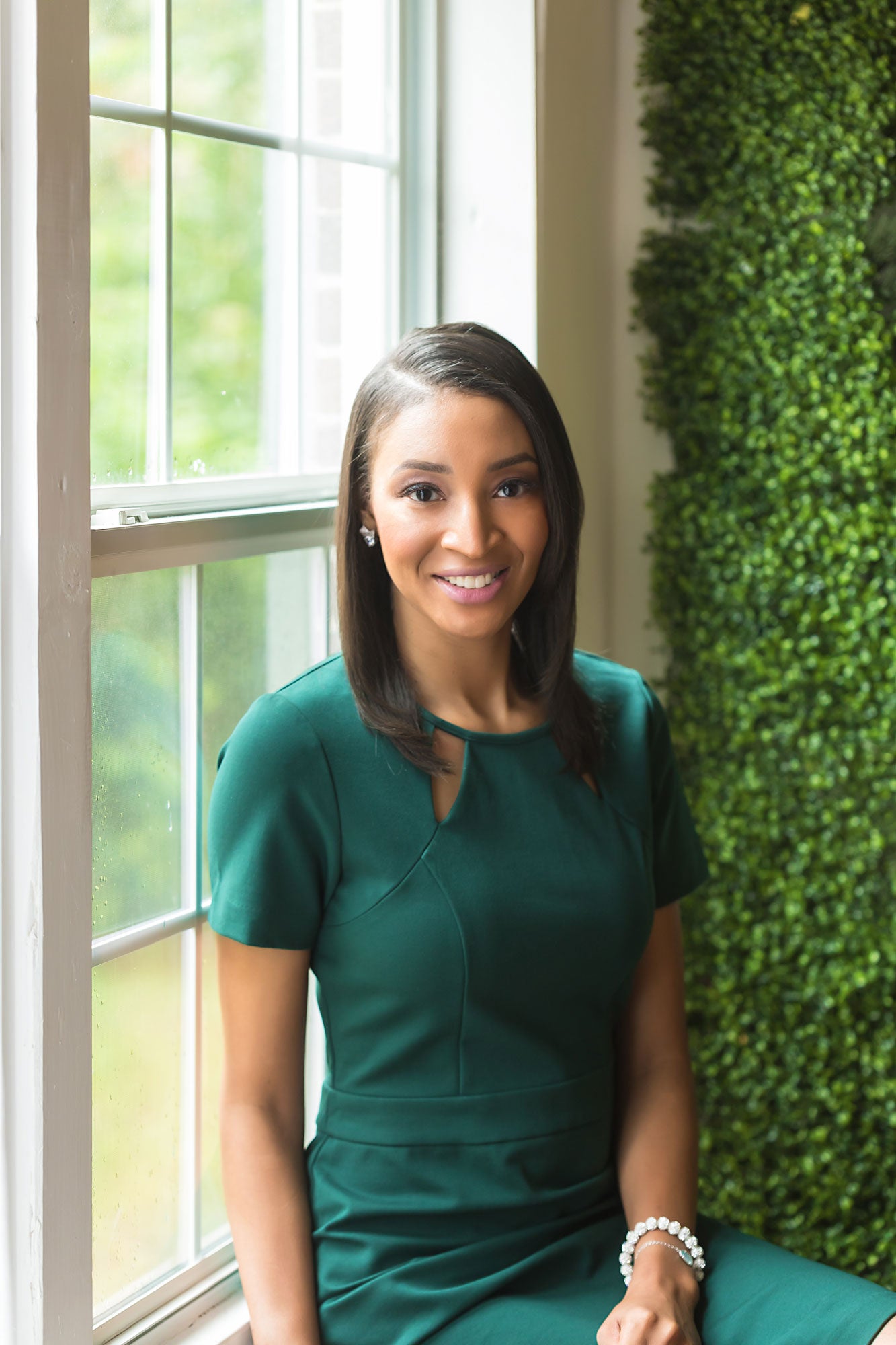 Brittany sitting in front of a window in green dress