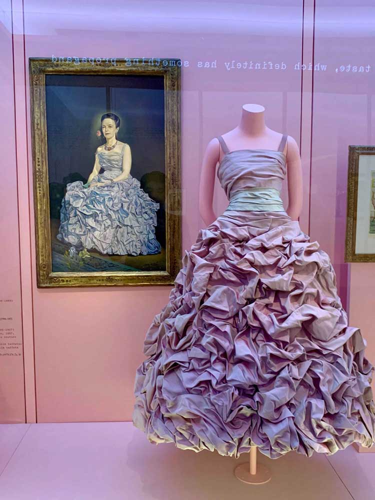 Photo of exhibit with purple dress and drawing in the background