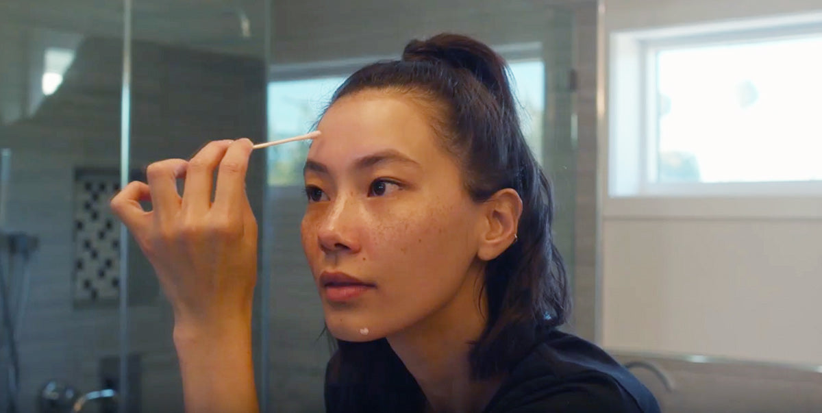 Woman applying spot treatment to face using cotton swab