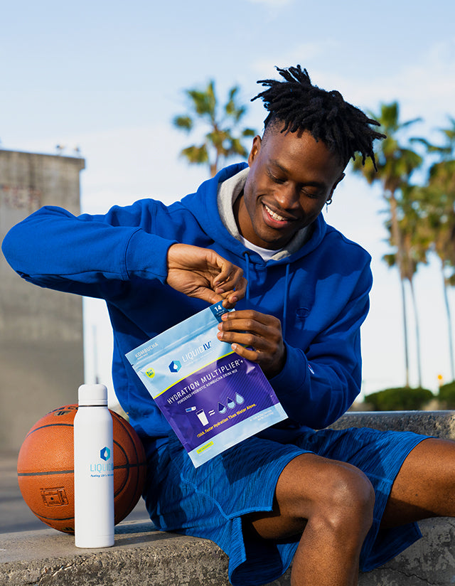 Man in blue sweatshirt with 14ct pouch of Kombucha Probiotic Powder