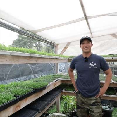 Man standing under high tunnel with microgreens in hawaii