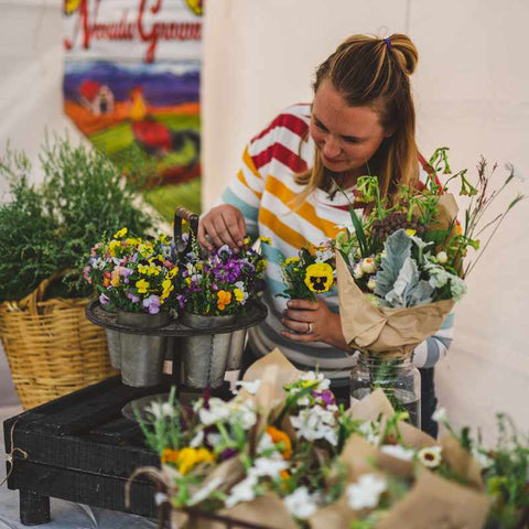 Jessica from Sierra flower farm arranging flowers at a flower popup stand.