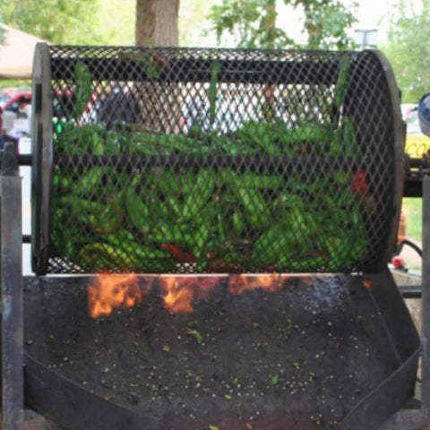 A chili roaster over open flame roasting hatch chiles at farmers market