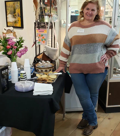 Melonie Johnes, Artist of the Month at Works of Wyoming,  poses in front of her Artist's reception table.