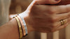 Inspirational bracelets in silver, gold, and rose gold offset on burlap with a leafy background