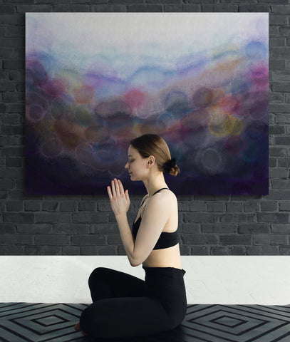 Large dramatic purple abstract canvas print on charcoal coloured black brick wall with woman sat on floor meditating